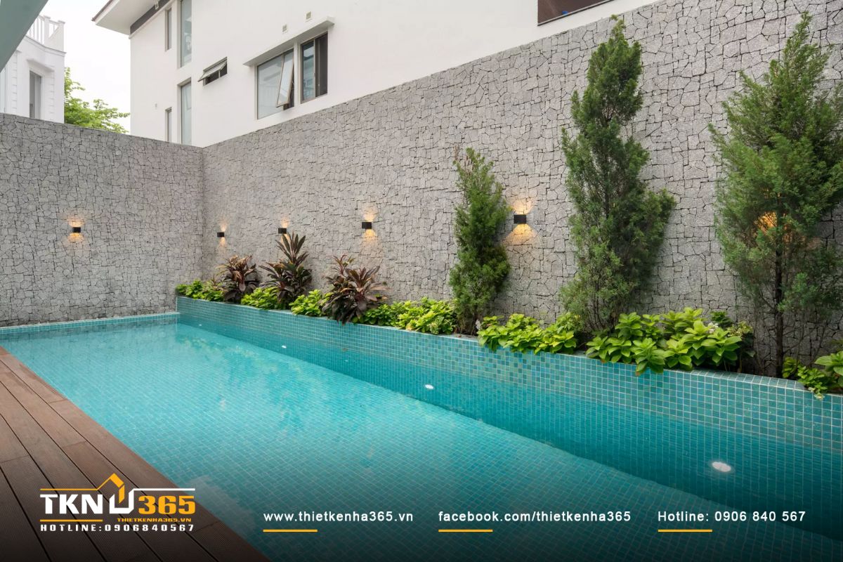 Hồ bơi có hình chữ nhật kết hợp với cây xanh tạo nên sự hài hòa giữa thiên nhiên và kiến trúc hiện đại