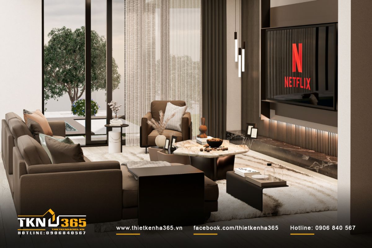 Phòng khách bố trí sofa nâu trầm và bàn đá vân mây, ánh sáng tự nhiên khuếch tán qua lớp rèm voan tạo cảm giác ấm áp, thư giãn