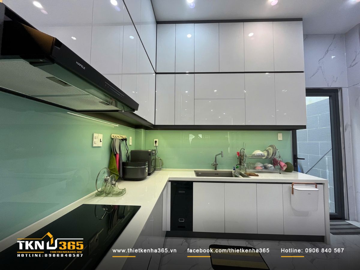 Căn bếp chữ L với hệ tủ bếp kịch trần , mặt đá sáng và kính ốp xanh mint giúp không gian luôn sạch sẽ, gọn gàng và dễ lau chùi