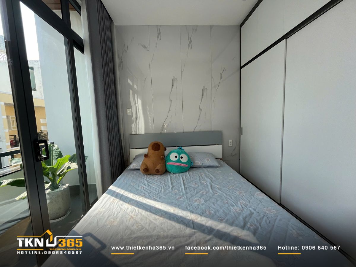 Giường ngủ đặt cạnh cửa kính đón nắng, mang lại cảm giác dễ chịu và thoáng đãng