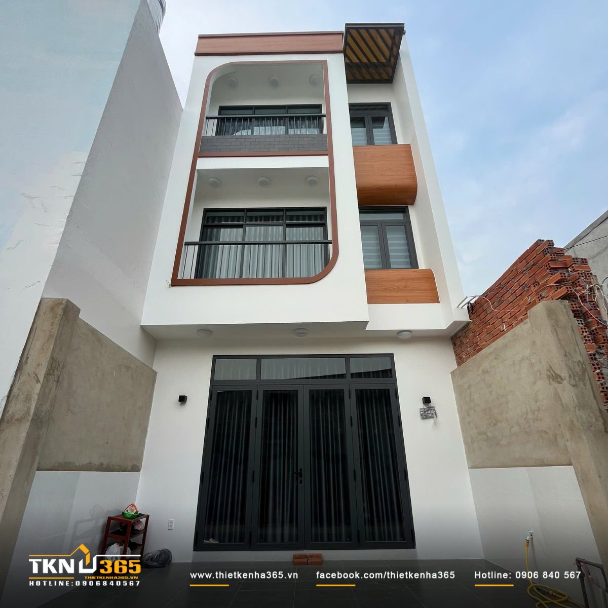 Mặt tiền nhà phố 3 tầng gây ấn tượng với đường cong mềm và mảng gỗ tạo điểm nhấn hiện đại