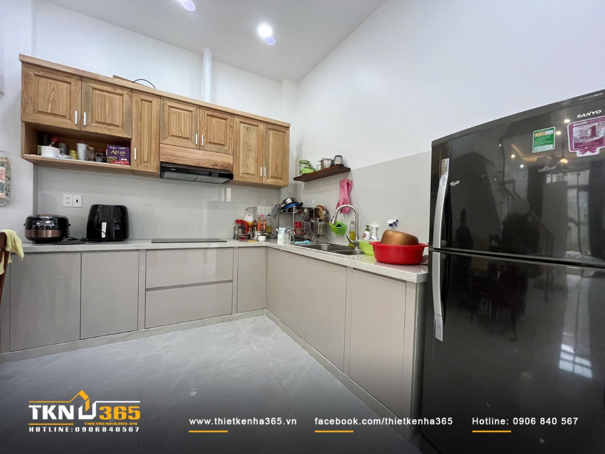 Bếp chữ L gọn gàng với hệ tủ gỗ sáng màu và mặt đá bóng sạch sẽ
