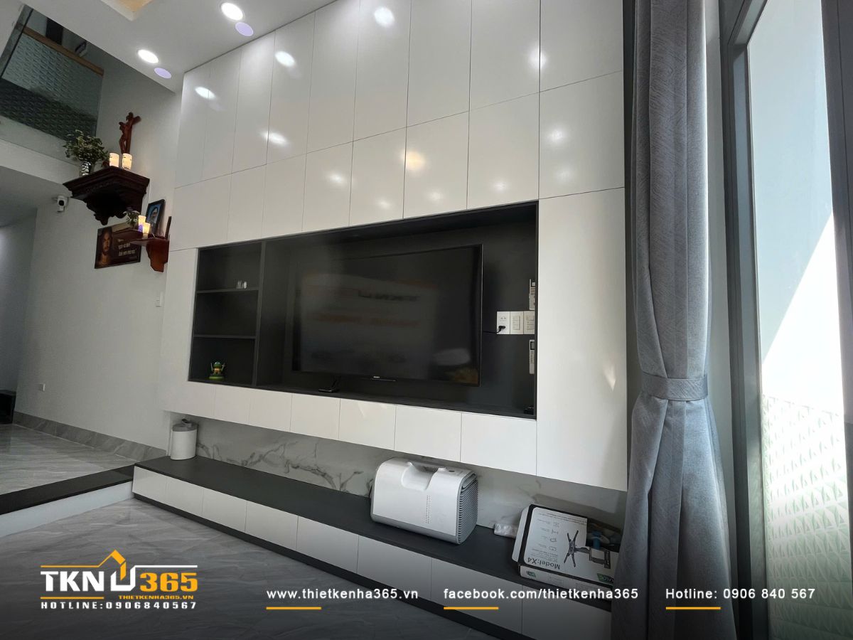 Ánh sáng tự nhiên khuếch tán qua rèm xám, làm nổi bật bề mặt vật liệu và sự gọn gàng của phòng khách