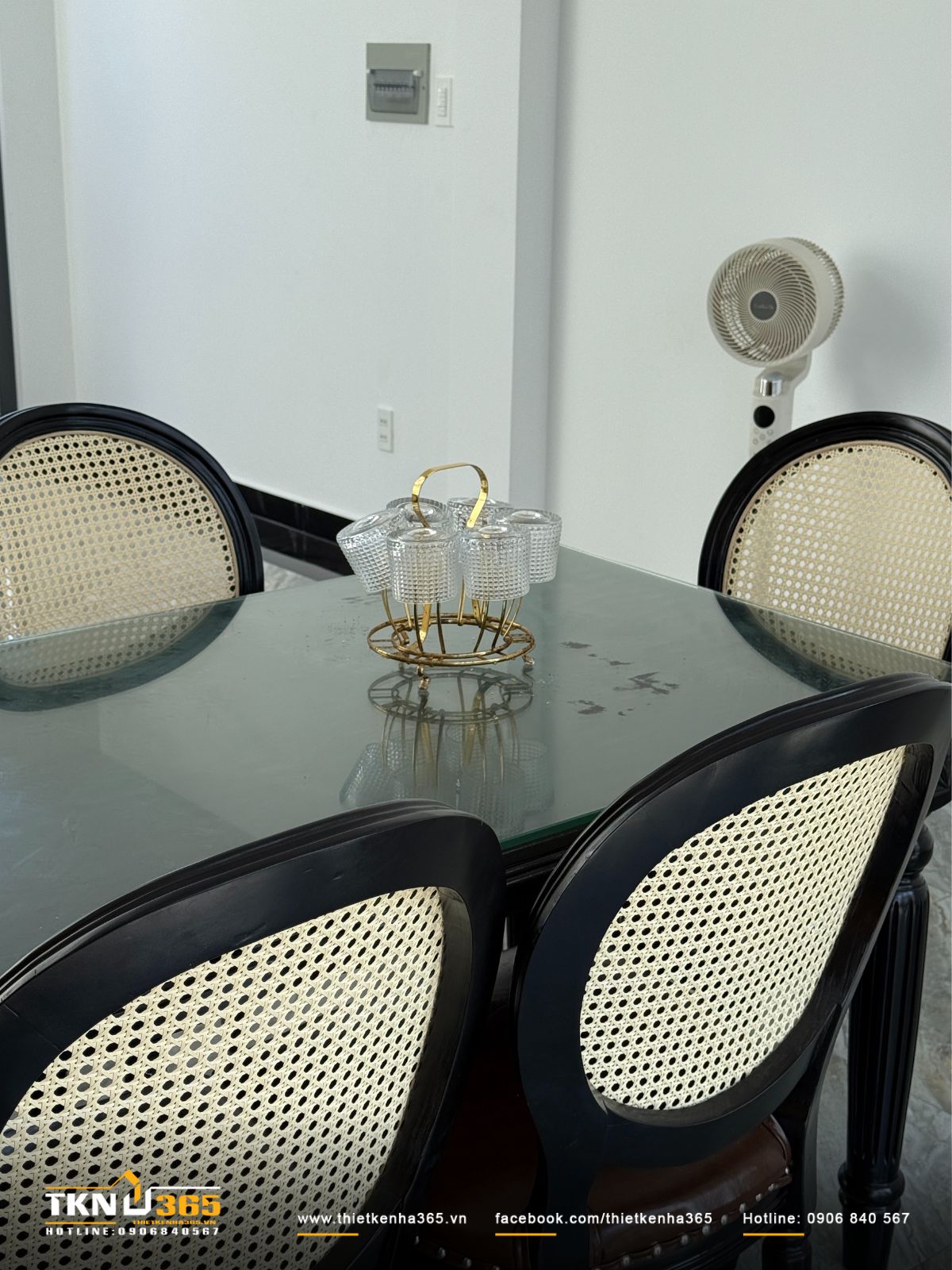 B&agrave;n ăn đặt tại trung t&acirc;m kh&ocirc;ng gian, thiết kế gọn g&agrave;ng với ghế m&acirc;y đan v&agrave; mặt b&agrave;n k&iacute;nh