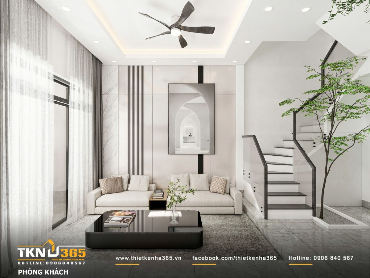 Ph&ograve;ng kh&aacute;ch bố tr&iacute; gọn g&agrave;ng với sofa t&ocirc;ng trung t&iacute;nh, b&agrave;n tr&agrave; mặt k&iacute;nh đen v&agrave; mảng tường trang tr&iacute; tiết chế, tạo chiều s&acirc;u thị gi&aacute;c cho kh&ocirc;ng gian hẹp